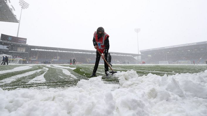 Burnley ground staff work to clear the pitch before the decision was made to postpone